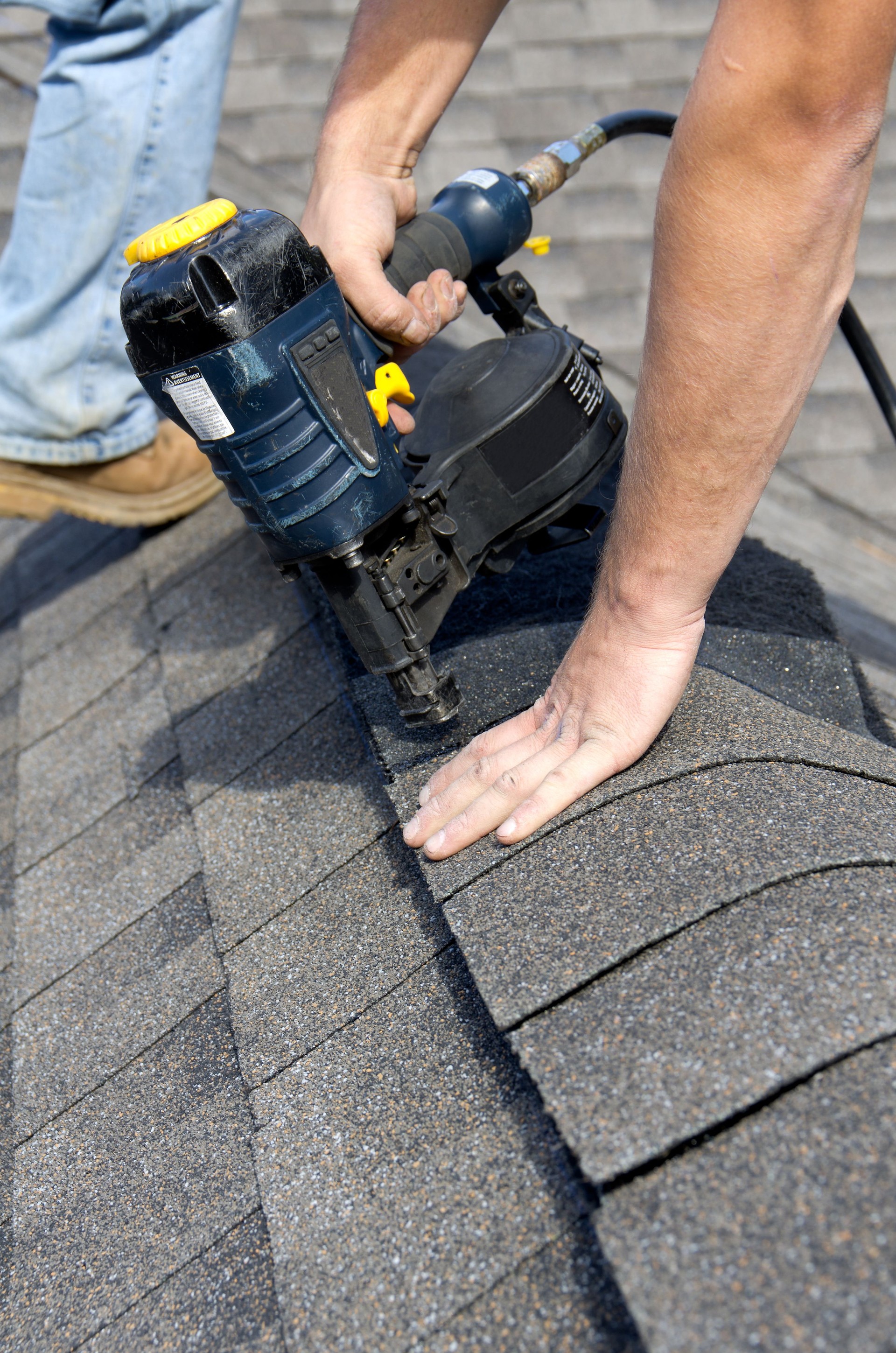 A man installing a shingles over a ridge